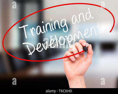 Man Hand writing Training and Development with black marker on visual screen Stock Photo