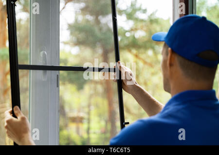 man installing insect mesh screen to protect room from mosquito Stock Photo