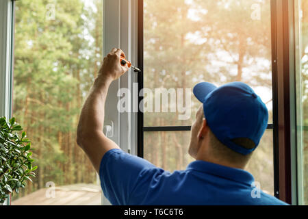 man installing mosquito net wire screen on house window Stock Photo