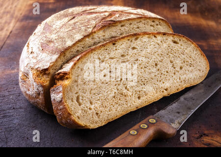 Freshly backed Farmhouse Bread sliced as close-up on an old burnt cutting board Stock Photo