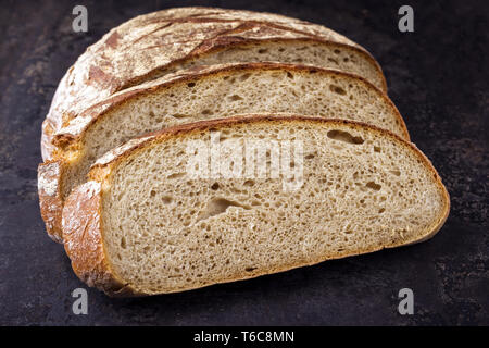 Freshly backed Farmhouse Bread sliced as close-up on an old griddle Stock Photo