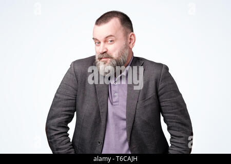 Cunning tricky mature man in jacket on white studio wall. Stock Photo