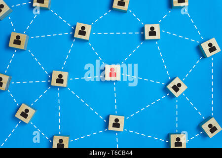 Leadership and network teamwork concepts Red businessman icon on the wooden block in the middle between the black business icon on the wooden blocks.  Stock Photo