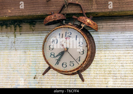 Old and rusty alarm clock, hanging by a nail in a shed, Kilwinning, Scotland Stock Photo