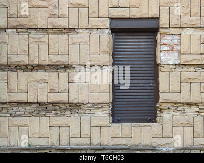 Black roll-metal door against old light brick wall, passage to the store or theater, rear exit, free space for text Stock Photo