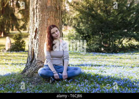 Dreamy young woman sitting in a flower meadow Stock Photo