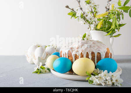 Easter cake, colored eggs on the event family table with cherry blossoms flowers as decor. Space for text. Stock Photo