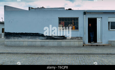 Fisherman next to a wall mural depicting the typical old portuguese fishing boats known as Moliceiros near the beach of Espinho, Portugal Stock Photo