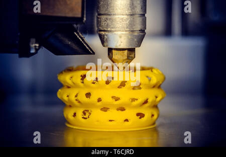 3d printer printing objects yellow form closeup. Modern technical 3D printing. Stock Photo