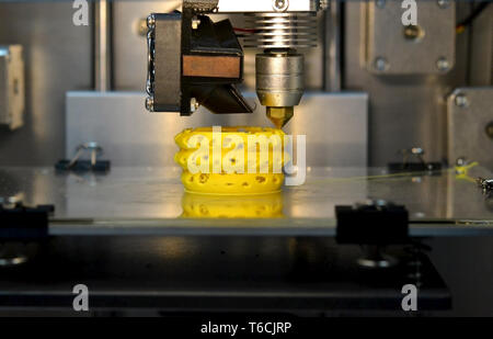 3d printer printing objects yellow form closeup. Modern technical 3D printing. Stock Photo