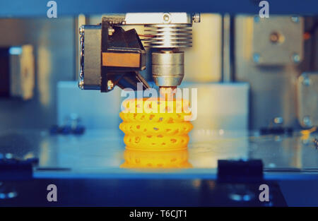 3d printer printing objects yellow form closeup. Modern technical 3D printing. Stock Photo