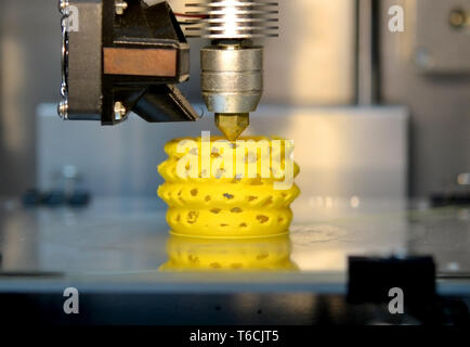 3d printer printing objects yellow form closeup. Modern technical 3D printing. Stock Photo