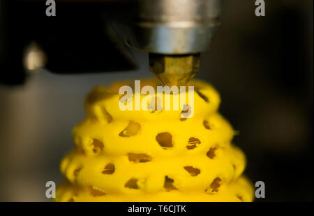 3d printer printing objects yellow form closeup. Modern technical 3D printing. Stock Photo