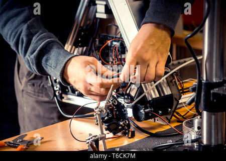 Two male masters work in the workshop with electronics, wires, 3d printer Stock Photo