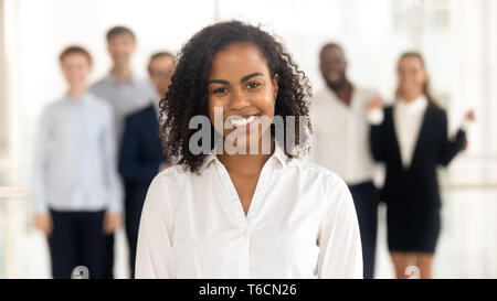 Smiling young mixed-race female worker intern standing looking at camera Stock Photo
