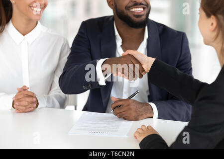 Happy mixed ethnicity couple handshaking broker sign mortgage contract Stock Photo