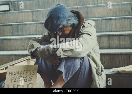 Homeless. Unhappy homeless man with black gloves is holding hand to get bit coins or help food donation from the people. Stock Photo