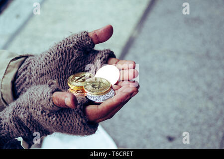 Homeless. Unhappy homeless man with black gloves is holding hand to get bit coins or help food donation from the people. Stock Photo