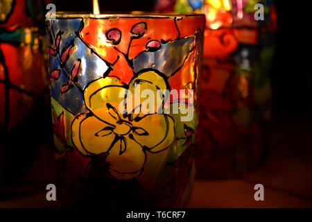 glass candle holder painted stained glass paints with a burning candle inside Stock Photo