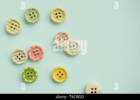 Wooden buttons with colored stripes and colorful dots on a pastel green background, sewing Stock Photo