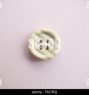 Isolated wooden button with colored colorful stripes on a light pink background, sewing Stock Photo