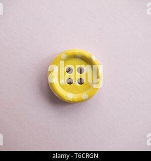 Isolated wooden button with colored colorful dots on a light pink background, sewing Stock Photo