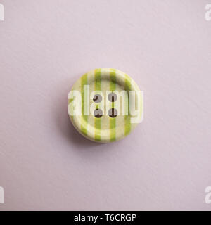 Isolated wooden button with colored colorful stripes on a light pink background, sewing Stock Photo