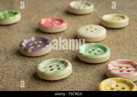 Wooden buttons with colorful stripes and colorful dots on a wooden background. Sewing Stock Photo