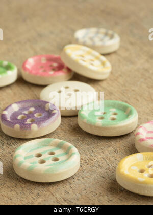 Wooden buttons with colorful stripes and colorful dots on a wooden background. Sewing Stock Photo