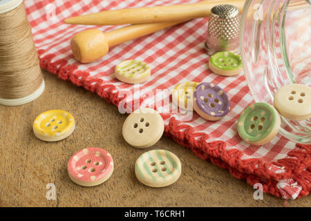 Wooden buttons with colored stripes of colors on a red and white checkered tablecloth, sewing Stock Photo