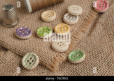 Wooden buttons with stripes of colored colors on a rustic fabric, sewing Stock Photo