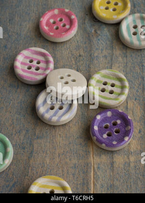 Wooden buttons with colorful stripes and colorful dots on a wooden background. Sewing Stock Photo