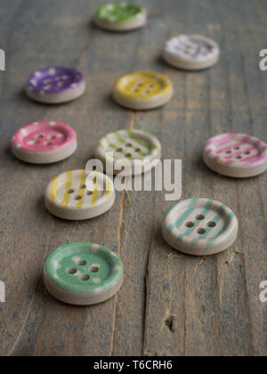 Wooden buttons with colorful stripes and colorful dots on a wooden background. Sewing Stock Photo