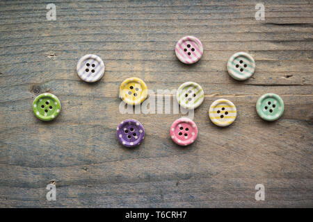 Wooden buttons with colorful stripes and colorful dots on a wooden background. Sewing Stock Photo