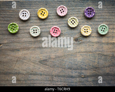 Wooden buttons with colorful stripes and colorful dots on a wooden background. Sewing Stock Photo
