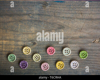 Wooden buttons with colorful stripes and colorful dots on a wooden background. Sewing Stock Photo
