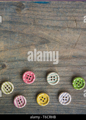 Wooden buttons with colorful stripes and colorful dots on a wooden background. Sewing Stock Photo