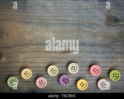 Wooden buttons with colorful stripes and colorful dots on a wooden background. Sewing Stock Photo