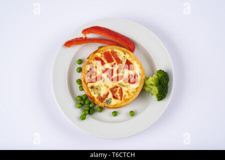 Broccoli cheddar mini savory pies on white plate. Delicious appetizers, snack, tapas. Flat lay. Tart or casserole with eggs, cheese, broccoli, bell, g Stock Photo