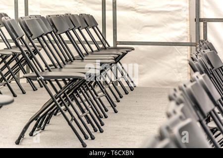 Rows of black folding chairs empty in a conference room Stock Photo
