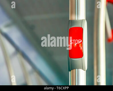 Red stop button on the metal handrail of a bus. Public transport. Public transportation Stock Photo