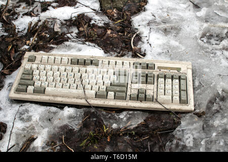 Abandoned dirty broken grunge computer keyboard on snowy frozen soil Stock Photo