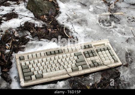 Abandoned dirty broken grunge computer keyboard on snowy frozen soil Stock Photo