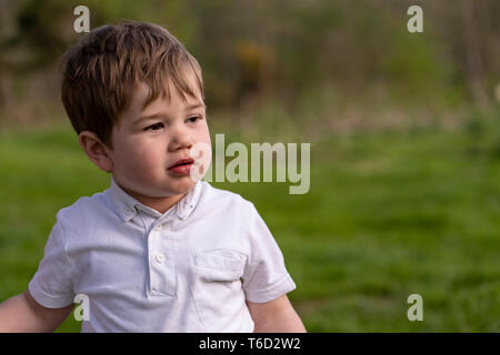 young boy outside in the park during summer, wearing white t-shirt Stock Photo