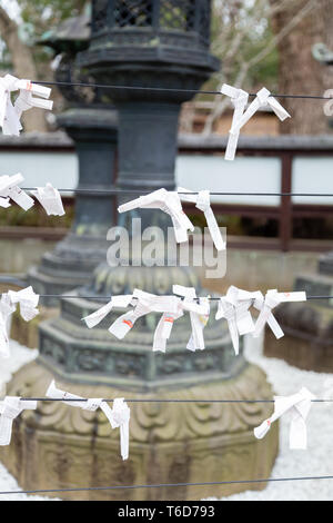 TOKYO, JAPAN - FEBRUARY 8, 2019: O-mikuji fotune papers in front of toro stone lanterns  at Toshogu Shrine, Ueno Park. Dedicated to shogun Tokugawa Ie Stock Photo