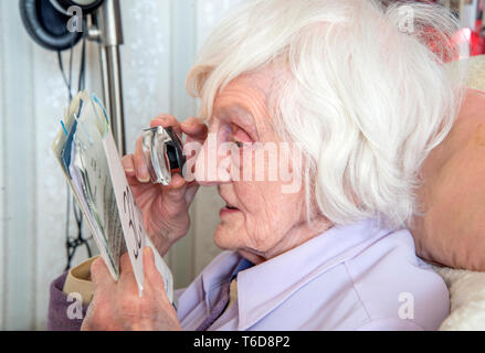 struggling to read text with a magnifying loupe for visually impaired people (VIP's) Stock Photo