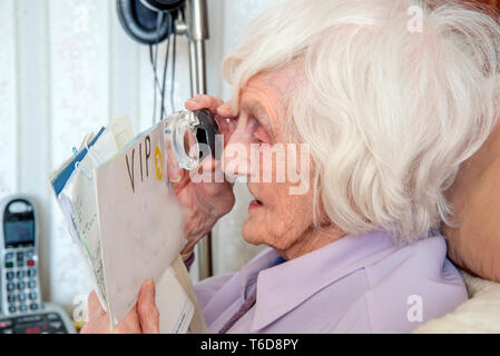 struggling to read text with a magnifying loupe for visually impaired people (VIP's) Stock Photo