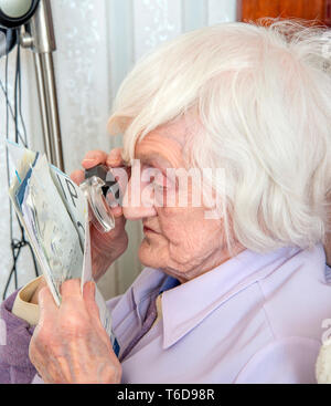 struggling to read text with a magnifying loupe for visually impaired people (VIP's) Stock Photo