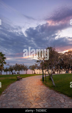 Stone pavement in a public park during sunset with heavy dark clouds. In Athens, Greece Stock Photo