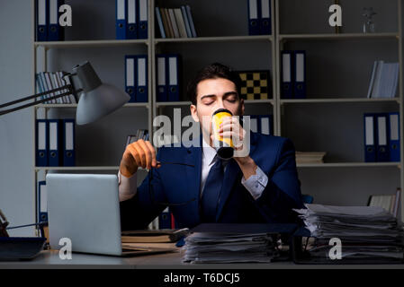 Employee working late and drinking strong coffee to stay awake Stock Photo